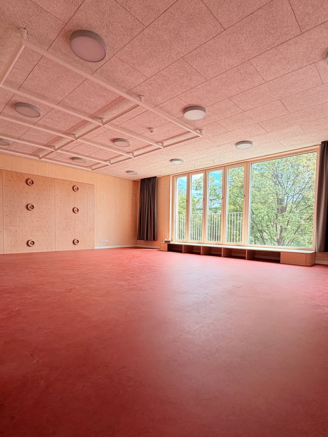 Heller Gruppenraum mit Sichtwänden aus Brettsperrholz und Fensterband