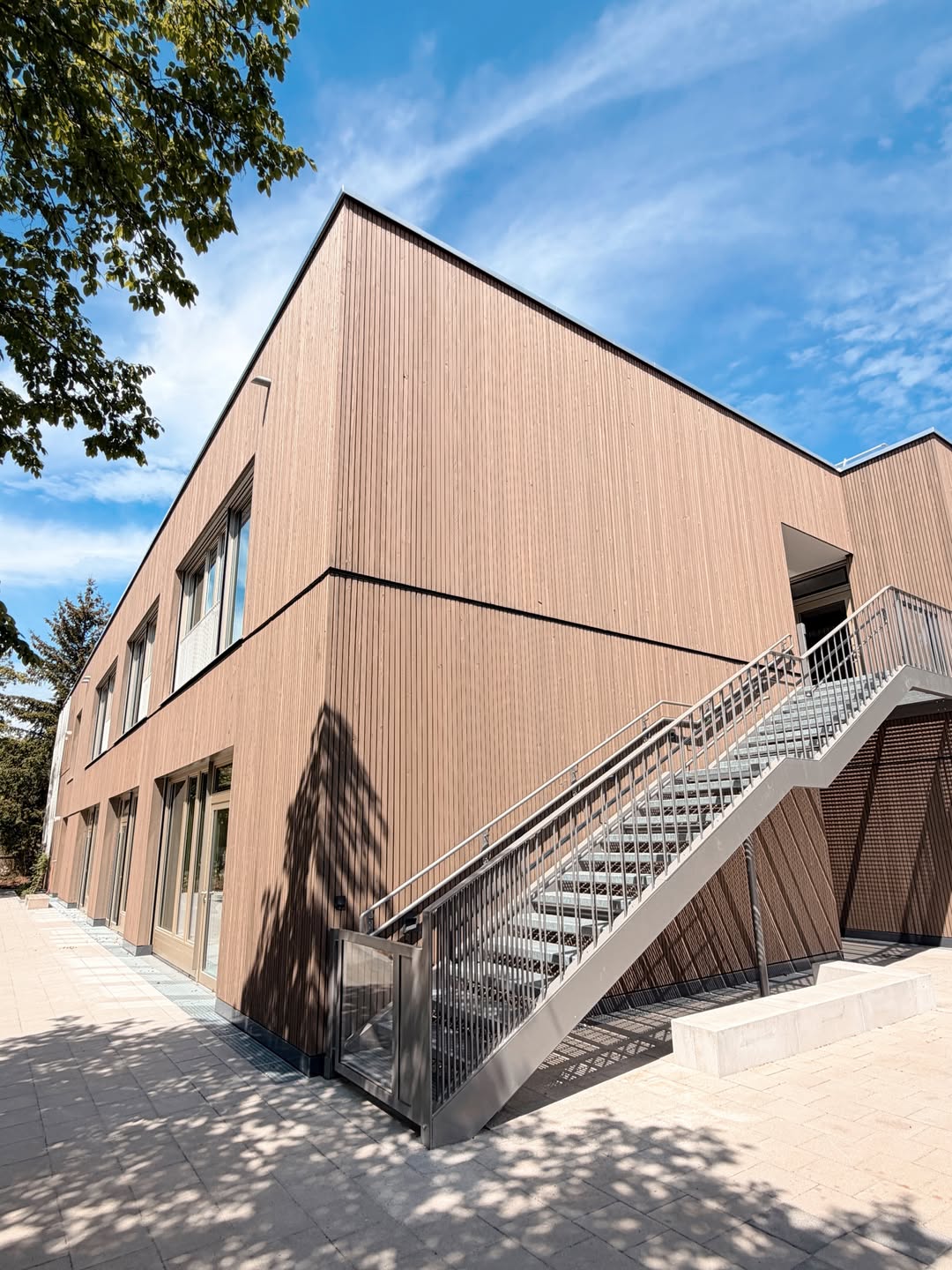 Außenansicht des Kindergartens mit Holzfassade und Stahltreppe